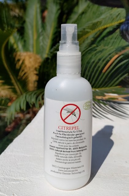 Weiße Sprühflasche des Insektenschutzmittels CITREPEL 75 mit transparentem Pumpspender auf heller Fläche. Etikett: durchgestrichenes Mückensymbol, 5 Std. Schutz durch Zitronengras, ECOCERT, für Kleinkinder. Hintergrund: grünes Laub.