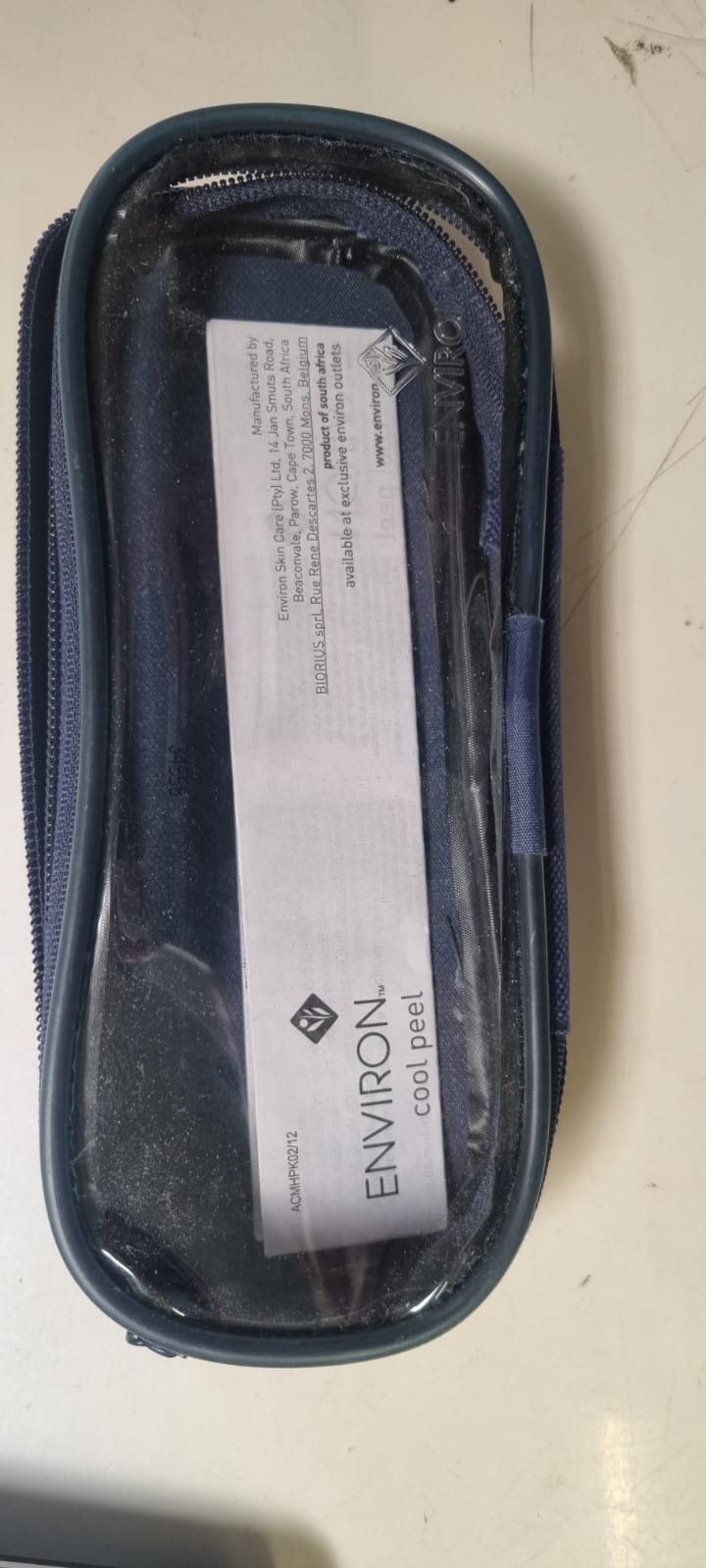 Kleines dunkelblaues Necessaire aus jeansähnlichem Stoff mit durchsichtigem Deckel, der das weiße Environ-Etikett innen zeigt. Mit Reißverschluss; ideal fürs Handgepäck auf Reisen, da wasserdicht.