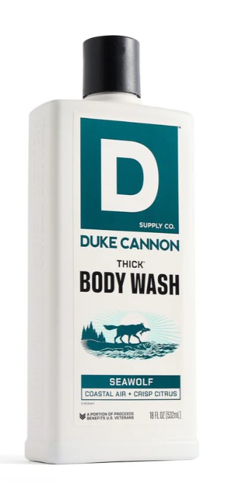 White rectangular bottle of DUKE CANNON THICK Body Wash with a black screw cap. Teal-green and white label featuring a wolf on a rocky coast, waves, trees and a halo. Text: "SEAWOLF COASTAL AIR + CRISP CITRUS", 532ml.