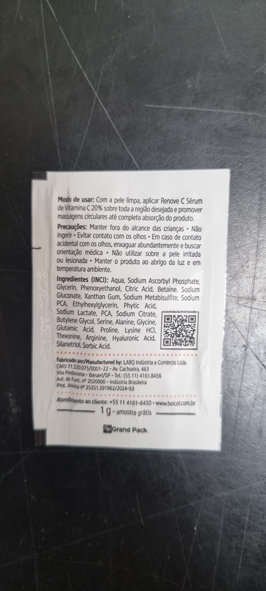 Gros plan sur un sachet blanc de BelCol RENOVE C SERUM (1 g de sérum de jour contenant 20 % de vitamine C). L'emballage en portugais indique clairement le mode d'emploi, les précautions d'emploi, la liste INCI, le code QR et les coordonnées.