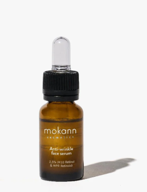 Amberfarbenes Serumfläschchen von Mokann Cosmetics mit schwarzem Tropfverschluss auf weißem Hintergrund mit leichtem Schatten. Etikett: 'Anti-wrinkle face serum' und '2,5% (H10 Retinol & HPR Retinoid)' Anti-Aging-Hautpflege.
