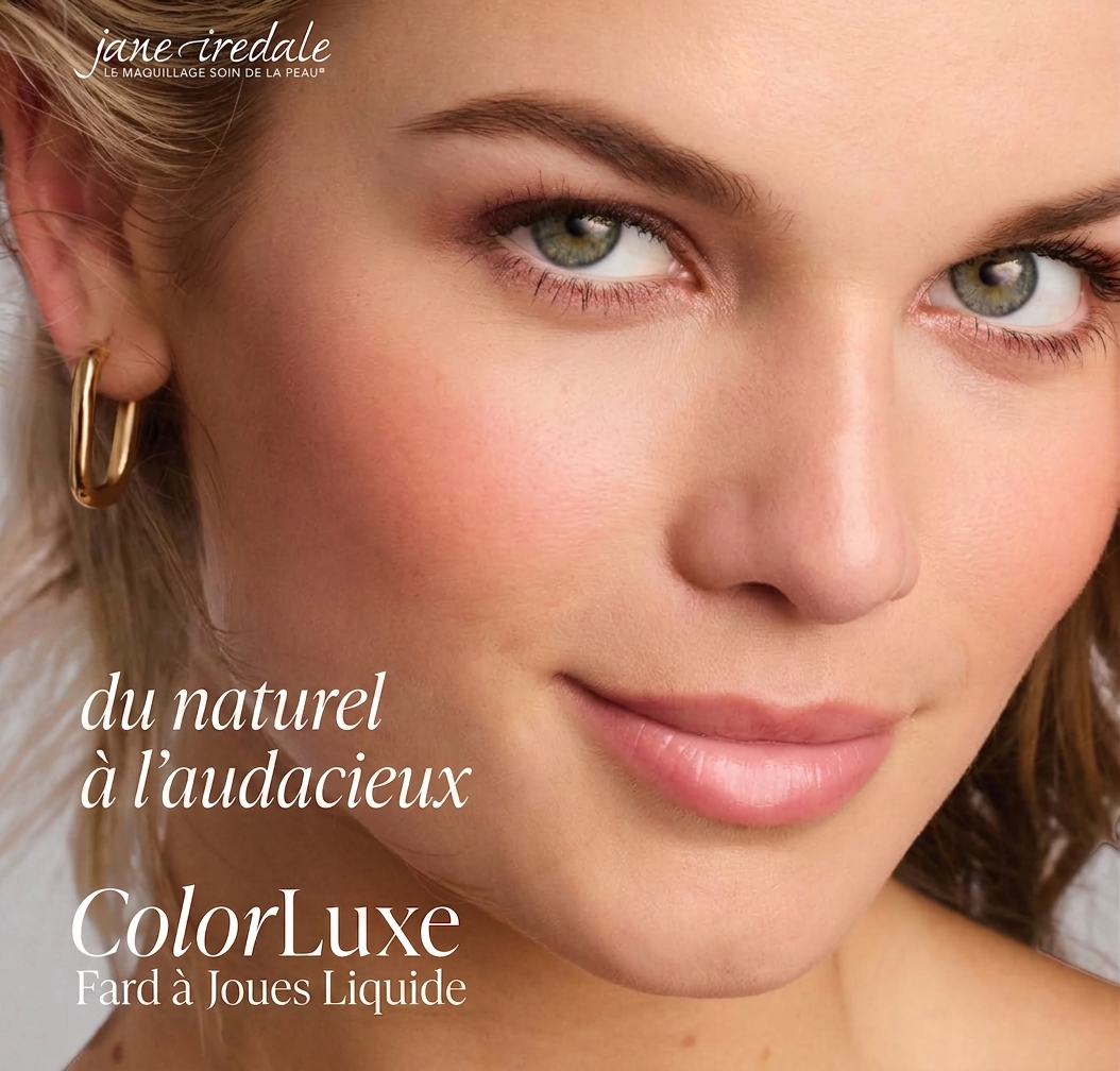 Gros plan sur le visage d'une jeune femme au léger sourire et aux yeux verts limpides. Teint impeccable, fard à joues rosé, lèvres pulpeuses rose tendre. Boucle d'oreille ovale en or à gauche. Regard franc et bienveillant.